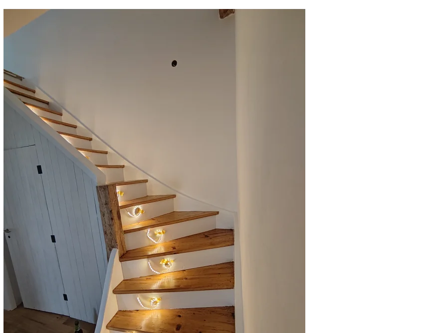 Beleuchtete Holztreppe mit weißem Geländer