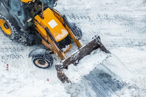 Traktor mit Schneeschild räumt Straße