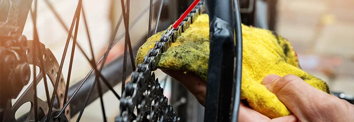 Person reinigt Fahrradkette mit Tuch