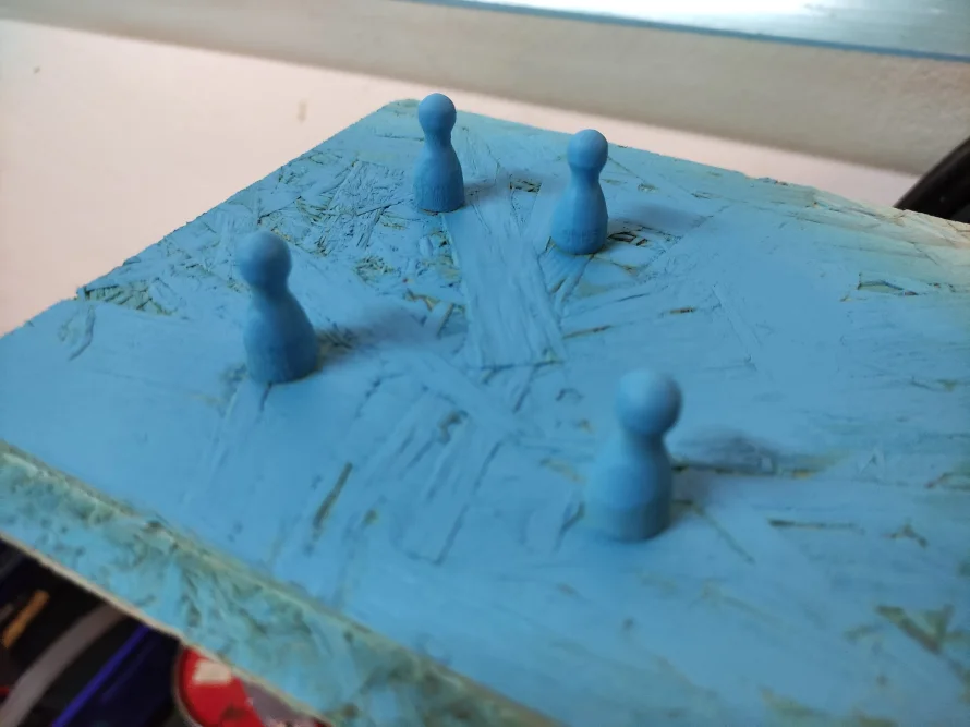 Vier blaue Spielfiguren auf blauer Fläche