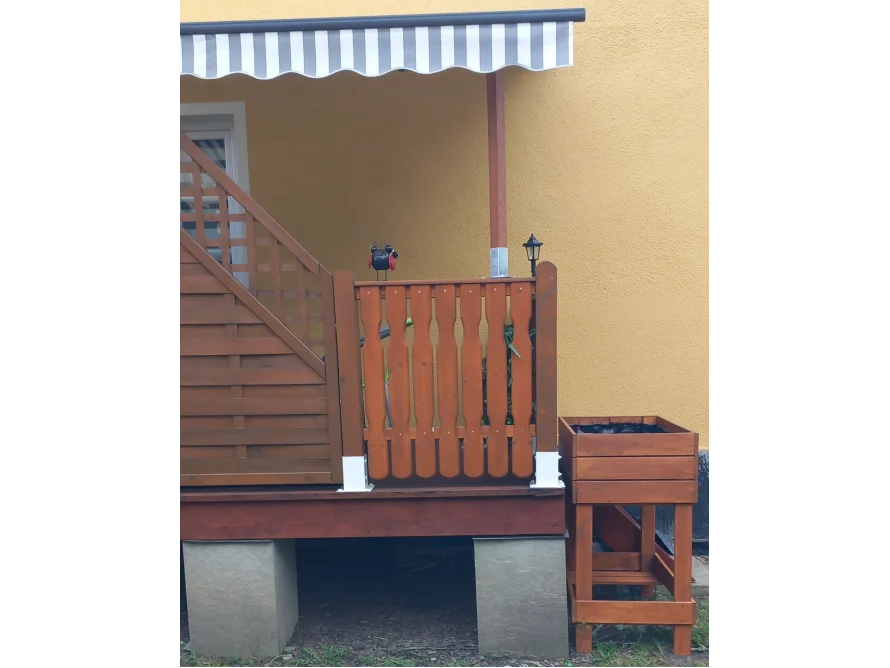 Holzterrasse mit Geländer und Hochbeet
