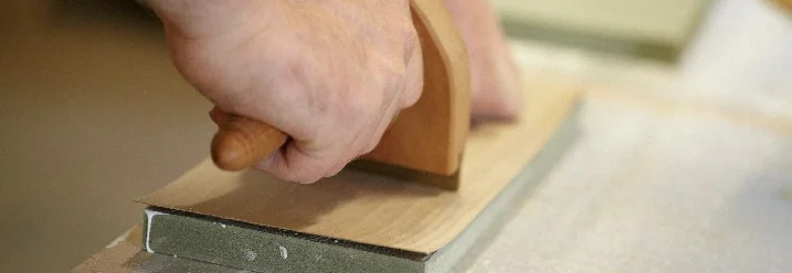 Holzfurnier wird auf einem Stück Holz angedrückt
