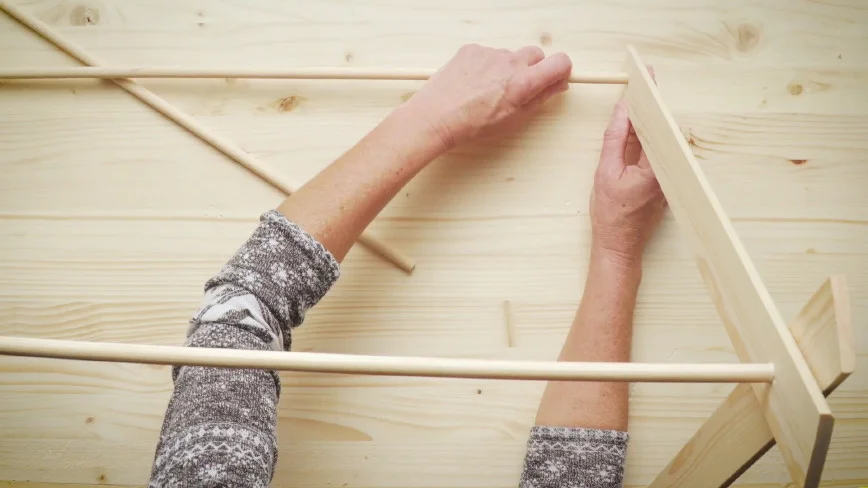 Person baut Holzgestell zusammen