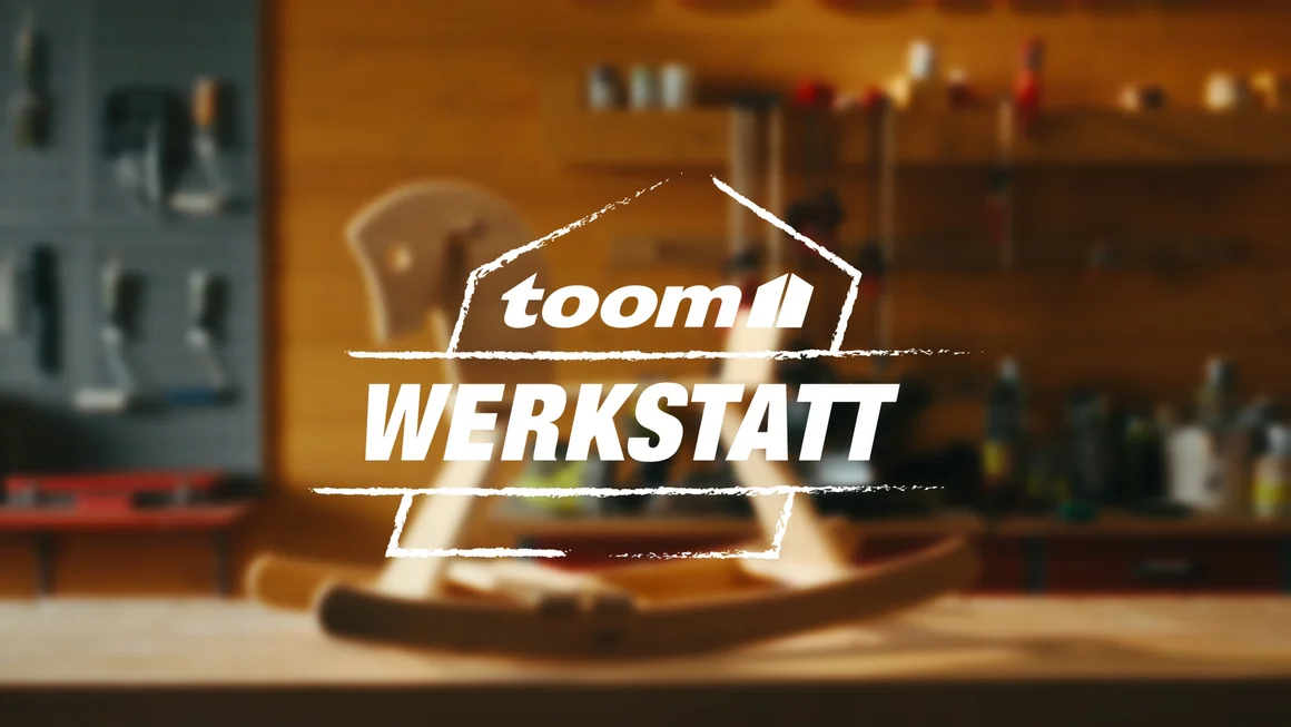 Unscharfe Werkstatt mit verschwommenem Schaukelpferd. Logo der toom Werkstatt