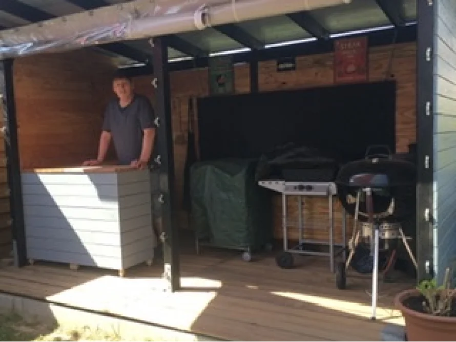 Person steht in einem Gartenhaus mit Grills