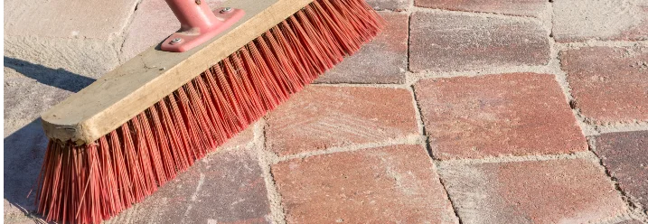Besen reinigt Pflasterfläche