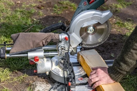 Person sägt Holz mit einer Kappsäge.