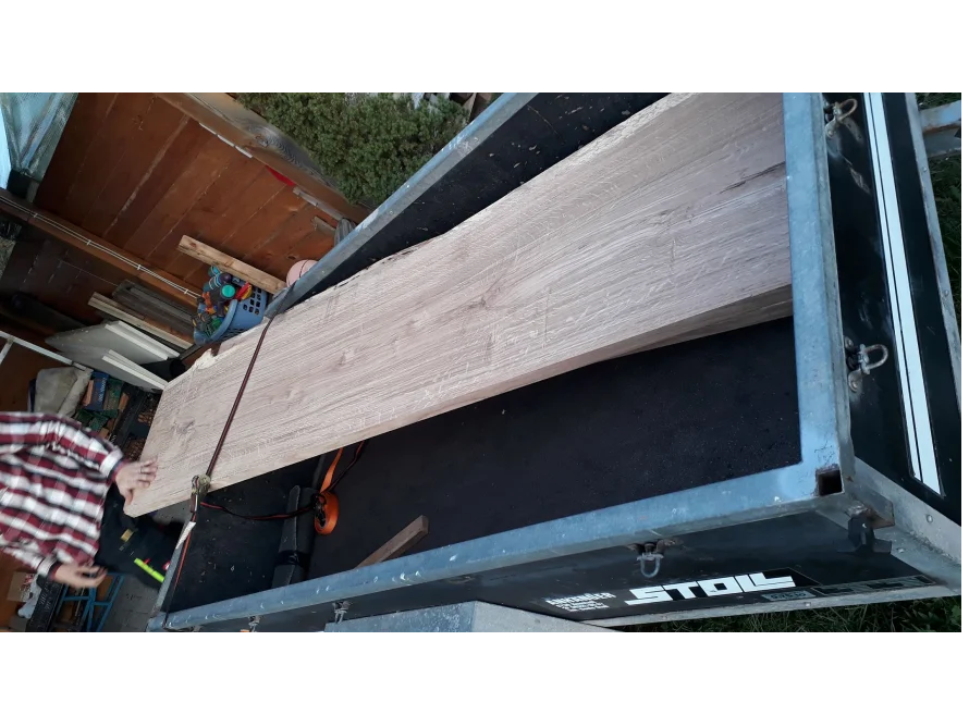Person befestigt Holzbrett mit Spanngurt