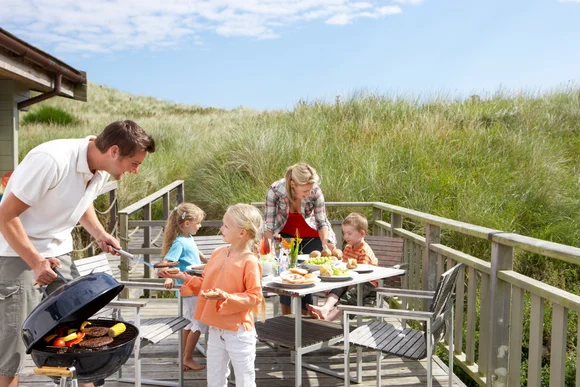 Familie grillt auf Holzterrasse