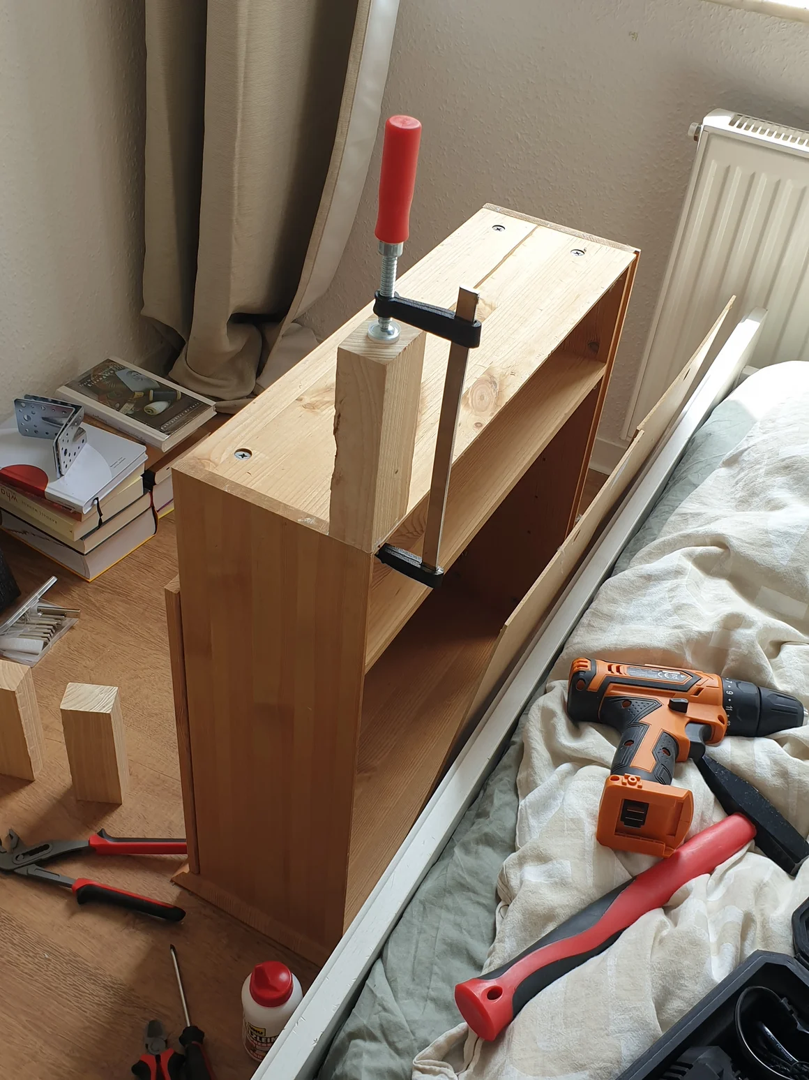 Eine Schraubzwinge fixiert ein Holzelement an einer Schublade.