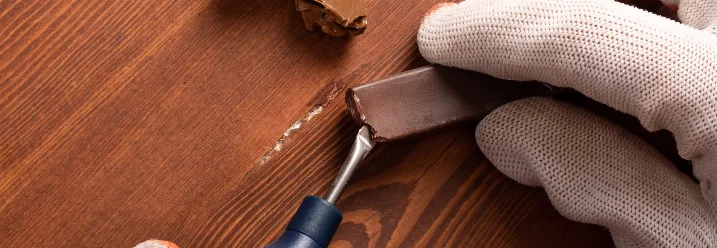 Person repariert Holzplatte mit Werkzeug