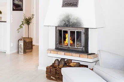 Kamin mit brennendem Feuer unterhalb einer rußverschmutzten Wand