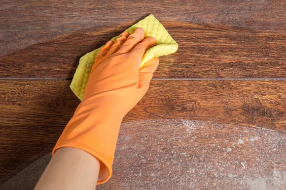 Hand reinigt Holzboden mit Schwamm
