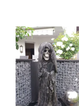 Skelettfigur mit Sense in einem Garten