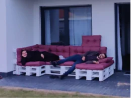 Zwei Personen entspannen auf einer selbstgebauten Palettensofa