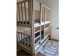 Ein Hochbett aus hellem Holz mit Rautenmuster-Teppich.