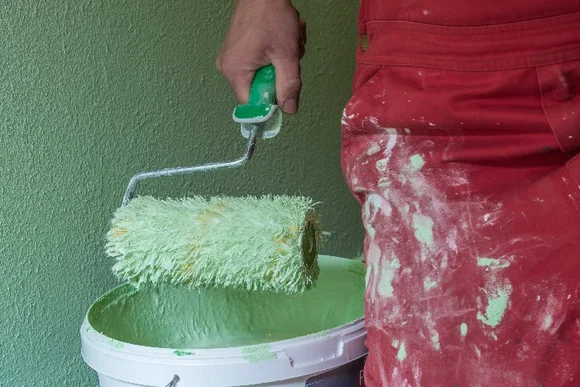 Person streicht Wand grün