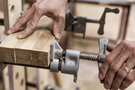 Drei Holzteile werden mit Schraubzwingen fixiert.