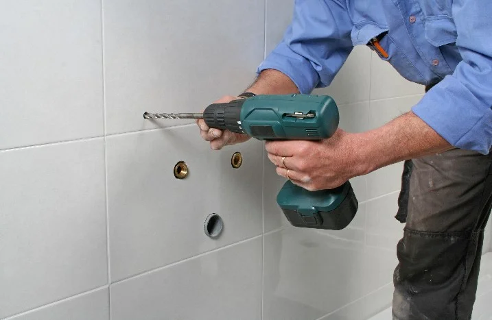 Person bohrt mit Bohrmaschine in Fliesen