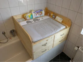 Ein Wickeltisch aus Holz über einer Badewanne.