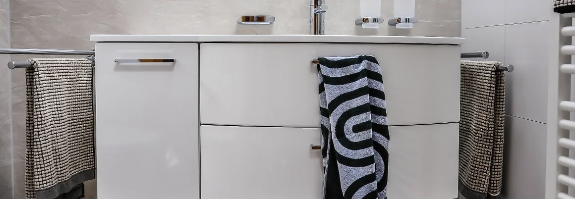 Modernes Badezimmer mit weißem Waschbecken und Handtüchern.