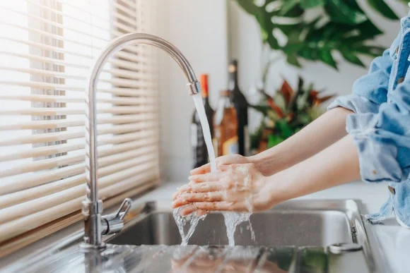 Person wäscht Hände unter Wasserhahn