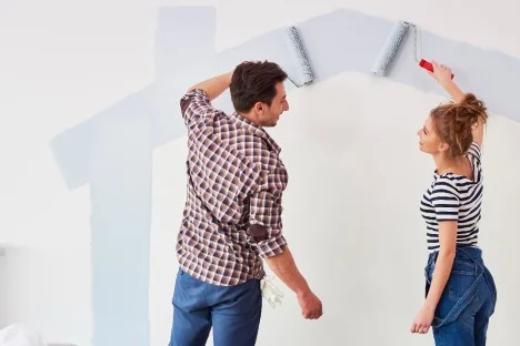 Zwei Personen streichen eine Wand