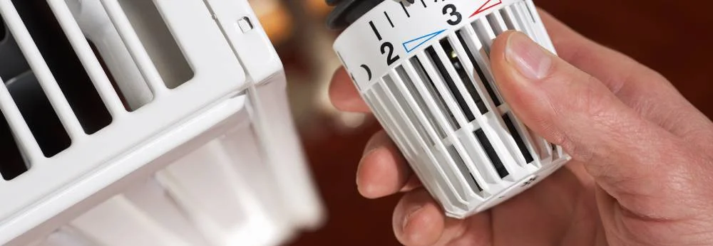 Person dreht an einem Thermostat