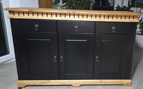 Schwarze Anrichte mit einer Platte und einem Sockel aus hellem Holz.
