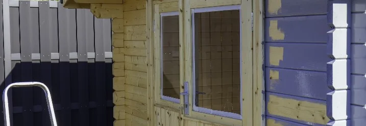 Ein Holz-Gartenhaus wird mit lila Farbe angestrichen
