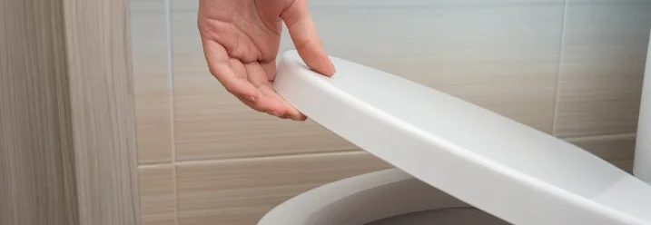 Hand hebt Toilettensitz an