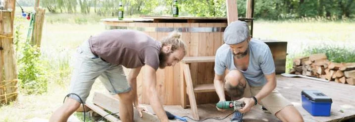 Zwei Personen bauen einen Holzboden mit Akkuschrauber