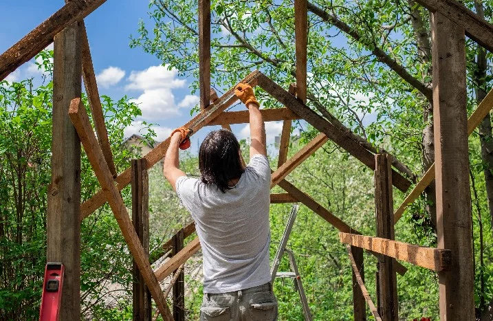 Person baut eine Pergola aus Holz.