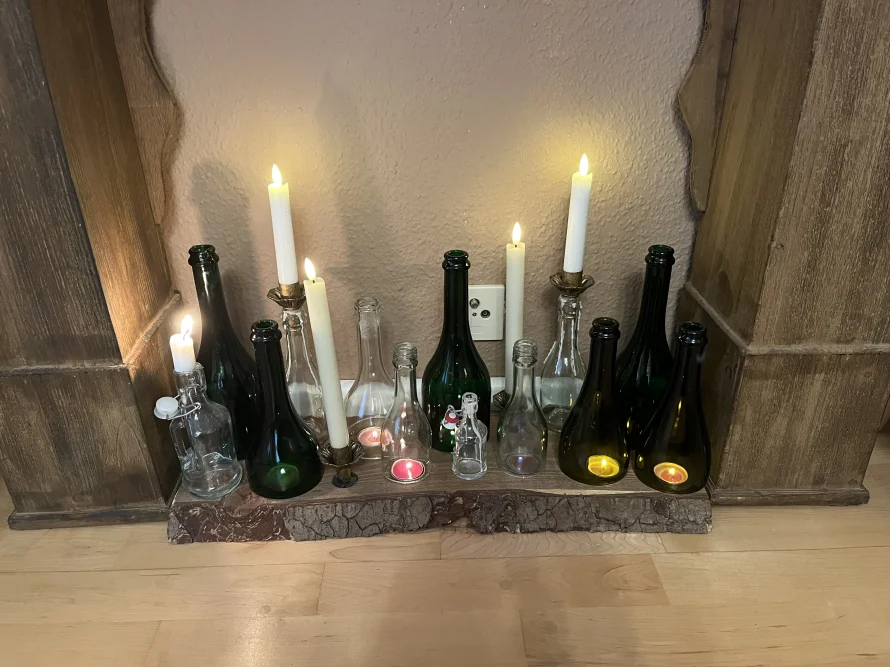 Glasflaschen und Kerzen auf einem Massivholzbrett