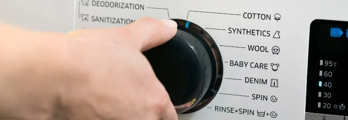 Hand wählt Waschprogramm an Waschmaschine