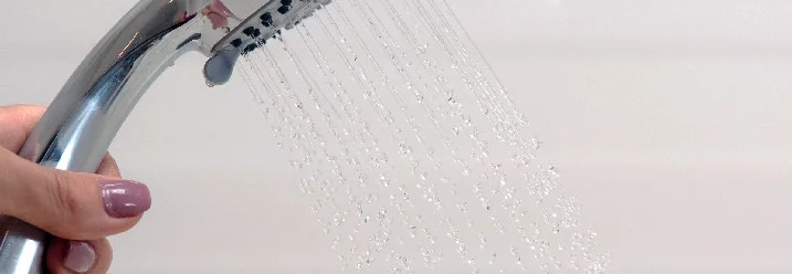 Hand hält Duschkopf mit Wasserstrahl