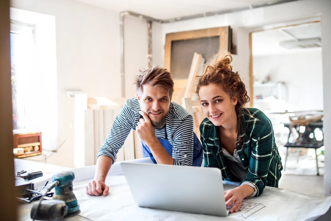 Zwei Personen mit Laptop und Bauplan