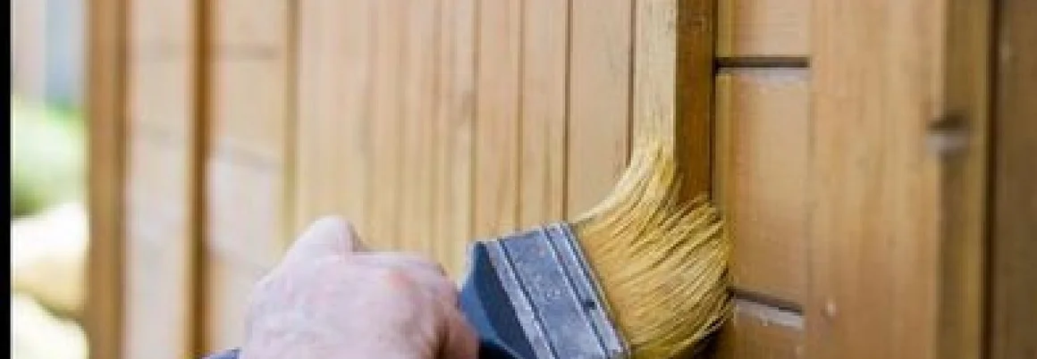 Person streicht Holz mit Pinsel