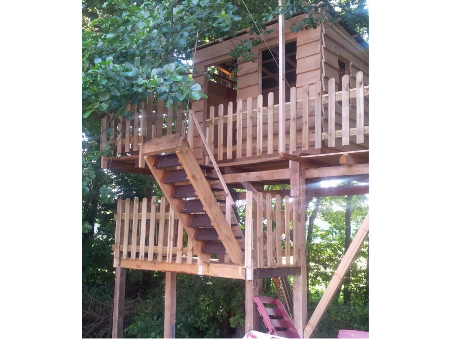 Ein Baumhaus aus Holz mit Zaun und Treppe.