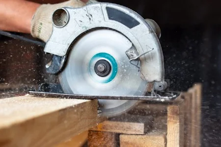 Person sägt Holz mit Kreissäge