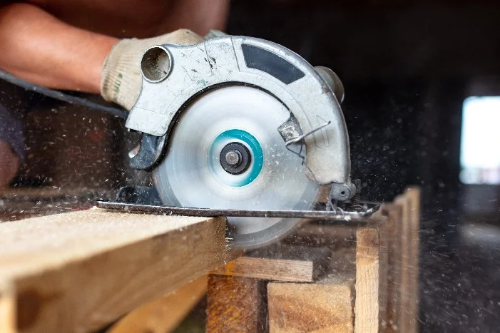 Person sägt Holz mit Kreissäge