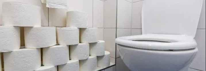 Toilette mit einem Stapel Toilettenpapier daneben