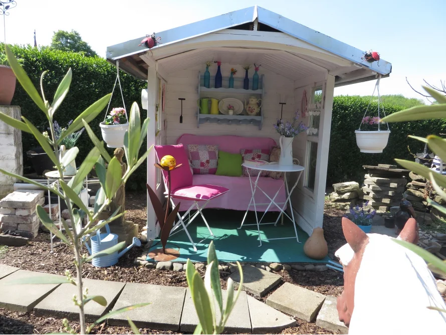 Gemütliches Gartenhäuschen mit rosa Sitzbank