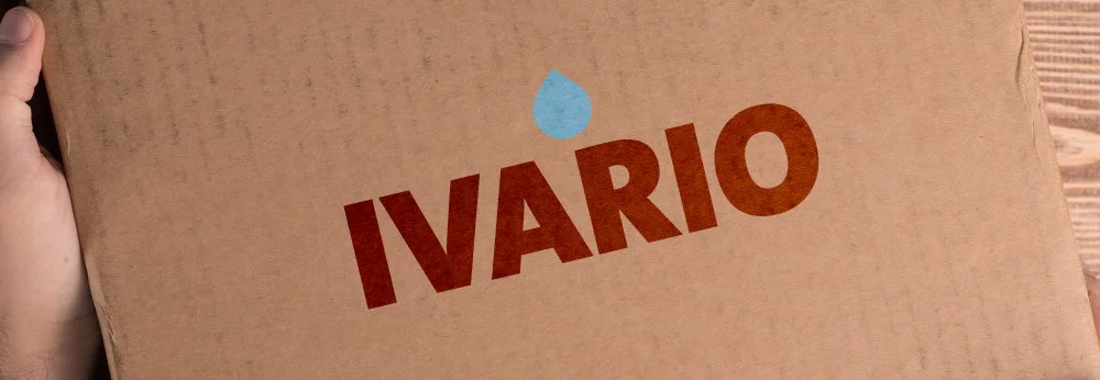 Hände halten einen Karton. Auf dem Karton steht Ivario geschrieben. 