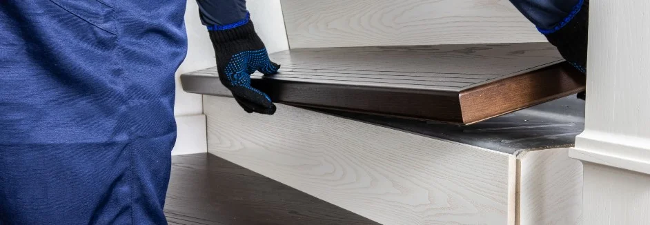 Person montiert Holzstufe auf Treppe