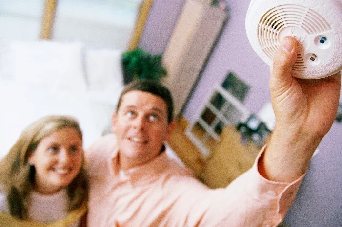 Zwei Personen halten einen Rauchmelder an die Decke