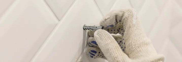 Hand mit Dübel an weißen Fliesen