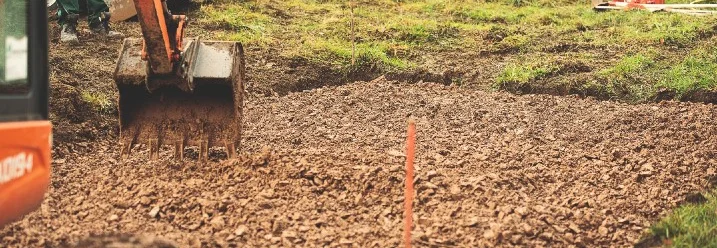 Bagger gräbt Erde für Fundament aus
