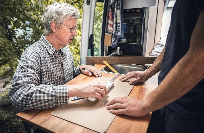 Zwei Personen bauen einen Campervan aus.