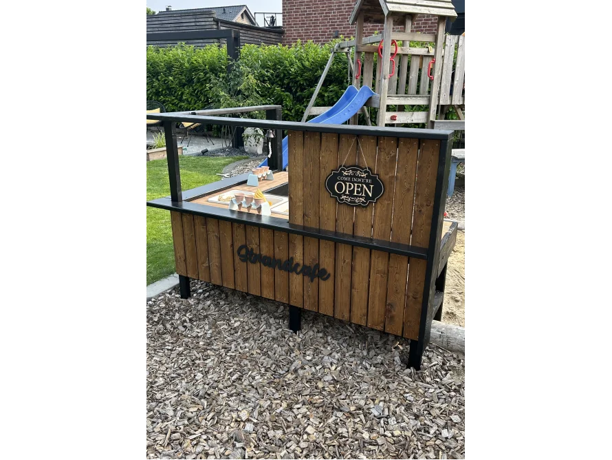 Ein selbstgebautes Strandcafé aus Holz für Kinder im Garten.